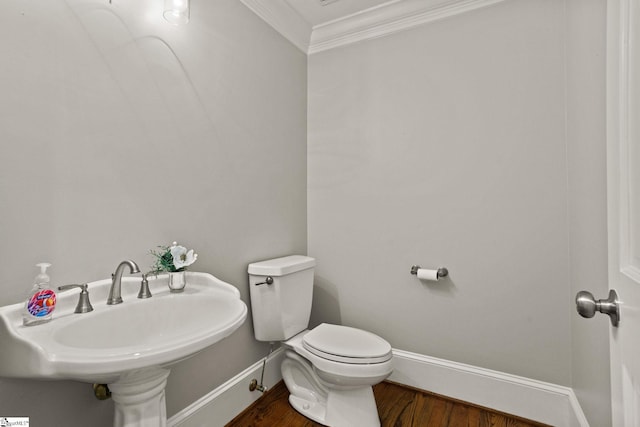 bathroom with crown molding, toilet, a sink, wood finished floors, and baseboards