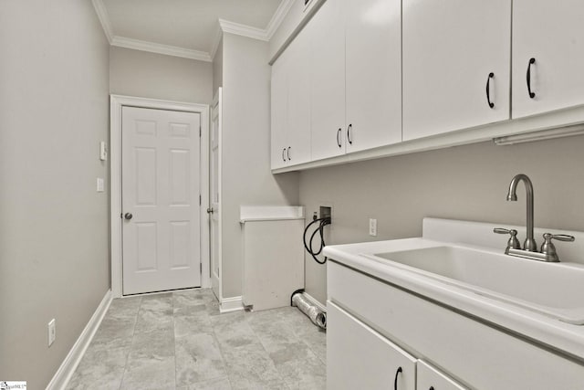 clothes washing area with hookup for a washing machine, cabinet space, ornamental molding, a sink, and baseboards