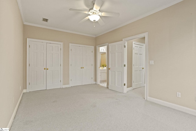 unfurnished bedroom with light carpet, baseboards, visible vents, crown molding, and multiple closets