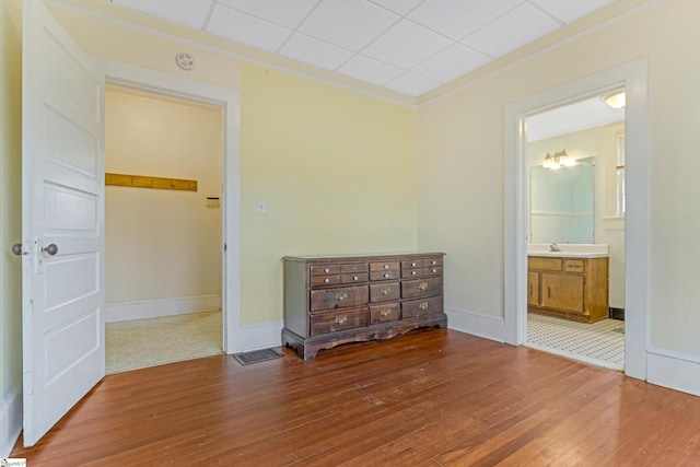 interior space with a sink, wood-type flooring, baseboards, and crown molding