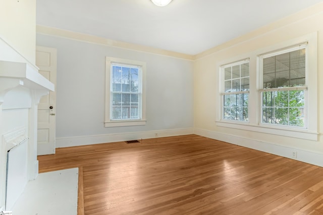 unfurnished room with visible vents, wood finished floors, a wealth of natural light, and baseboards