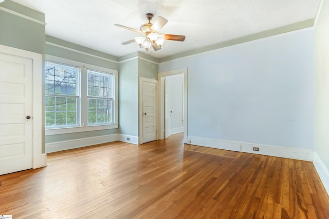 spare room featuring a textured ceiling, wood-type flooring, a ceiling fan, and baseboards