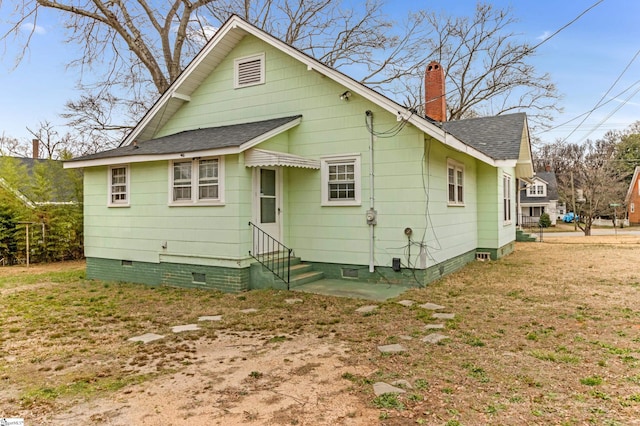 back of property with entry steps, roof with shingles, crawl space, and a chimney