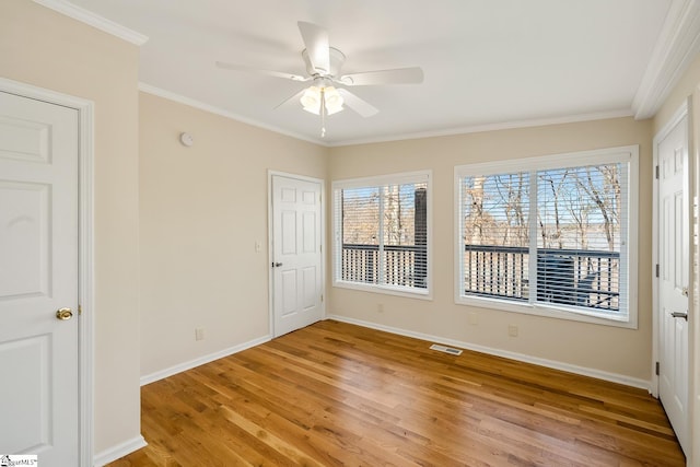 empty room featuring light wood-type flooring, a healthy amount of sunlight, visible vents, and crown molding