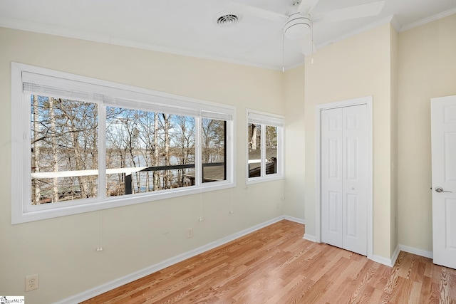 unfurnished bedroom featuring visible vents, baseboards, ornamental molding, a closet, and light wood finished floors