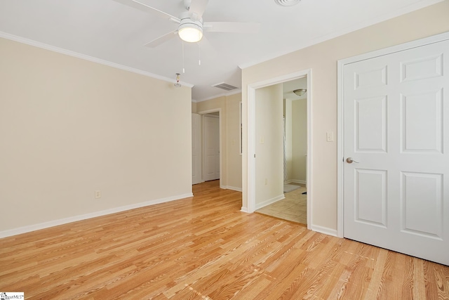 empty room with crown molding, light wood finished floors, visible vents, a ceiling fan, and baseboards