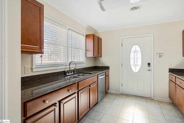 kitchen with visible vents, stainless steel dishwasher, brown cabinetry, a sink, and dark stone counters