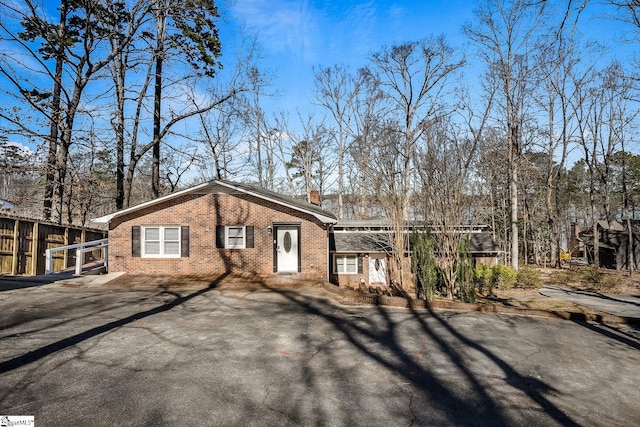 view of front of house with a chimney, fence, and brick siding