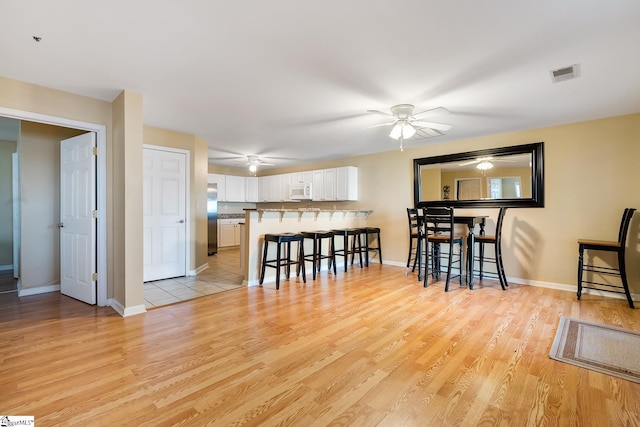 dining room with visible vents, ceiling fan, light wood-style flooring, and baseboards