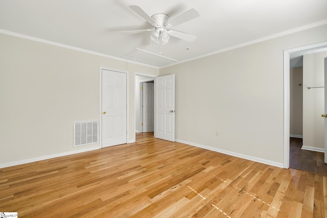 unfurnished bedroom with light wood-style flooring, visible vents, baseboards, attic access, and crown molding