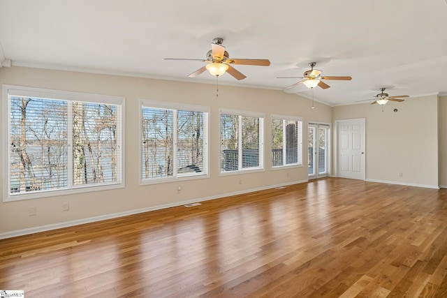 interior space featuring light wood-type flooring, a healthy amount of sunlight, lofted ceiling, and baseboards