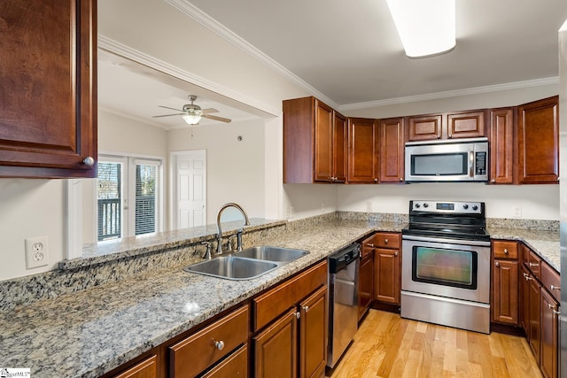 kitchen with light stone counters, light wood-style flooring, stainless steel appliances, a sink, and ornamental molding