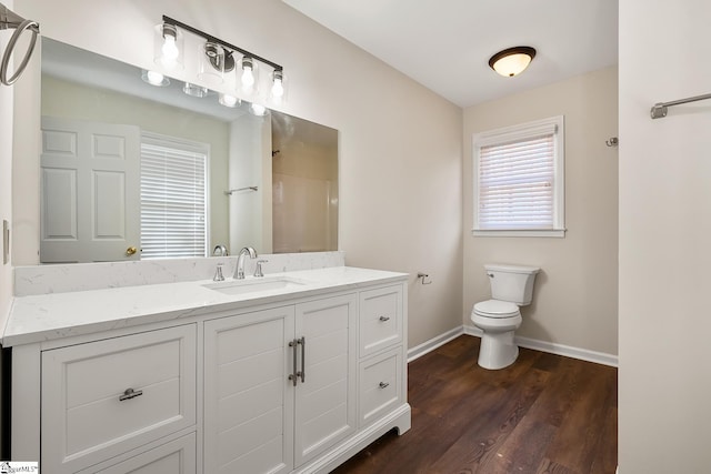 full bathroom featuring toilet, wood finished floors, vanity, baseboards, and a shower