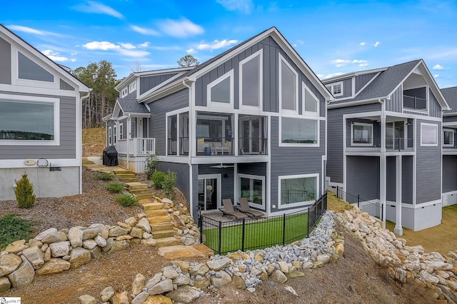 back of house featuring stairway, board and batten siding, a sunroom, and fence