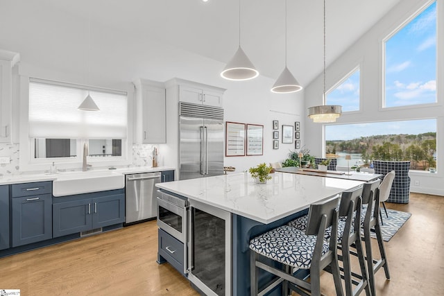 kitchen with wine cooler, decorative backsplash, a sink, built in appliances, and a kitchen breakfast bar