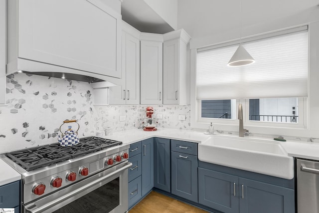 kitchen with stainless steel appliances, a sink, white cabinets, light countertops, and blue cabinetry