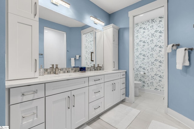 full bathroom featuring toilet, double vanity, baseboards, and a sink