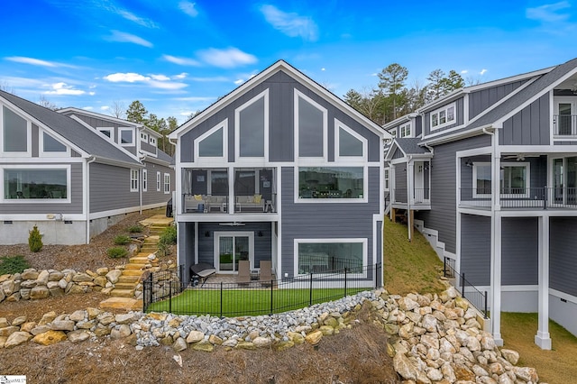 rear view of property with fence private yard, stairway, and a sunroom