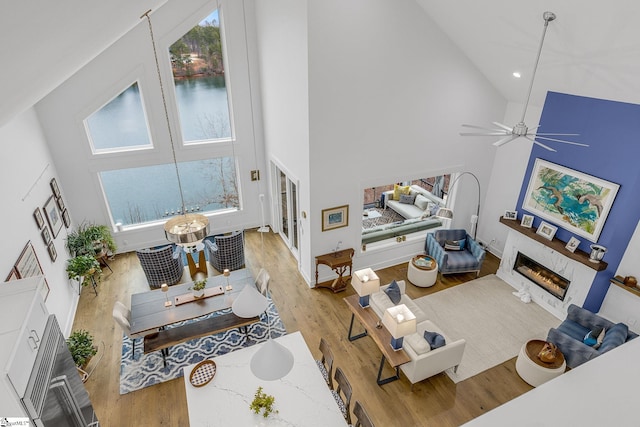 living area with ceiling fan, high vaulted ceiling, a tile fireplace, recessed lighting, and wood finished floors