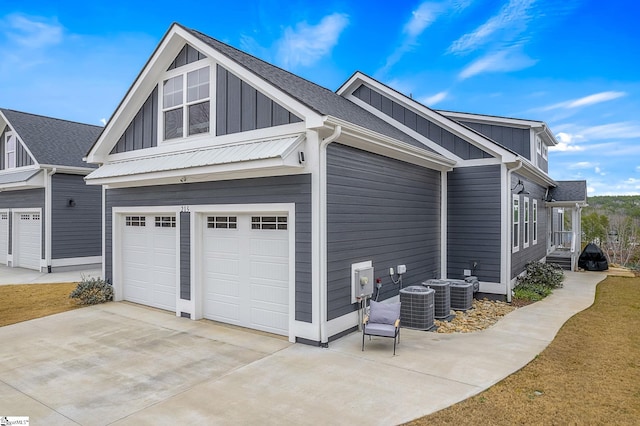 view of side of property with concrete driveway, board and batten siding, an attached garage, and cooling unit