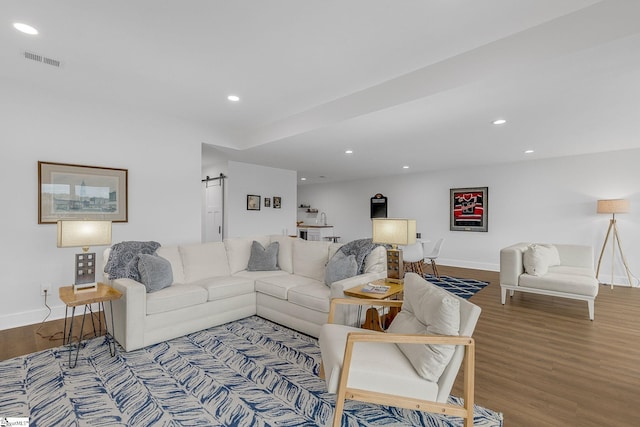 living area with recessed lighting, wood finished floors, visible vents, and a barn door