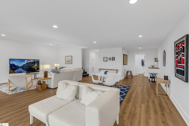 living area featuring baseboards, stairway, wood finished floors, and recessed lighting