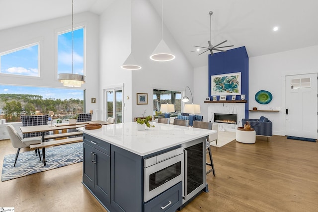 kitchen with wine cooler, a fireplace, wood finished floors, a center island, and stainless steel microwave