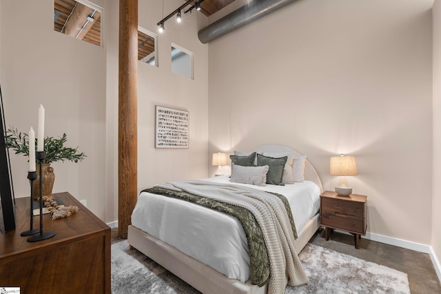 bedroom with a towering ceiling, baseboards, and track lighting