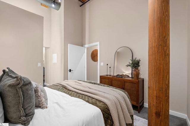 bedroom with a towering ceiling, baseboards, and dark colored carpet