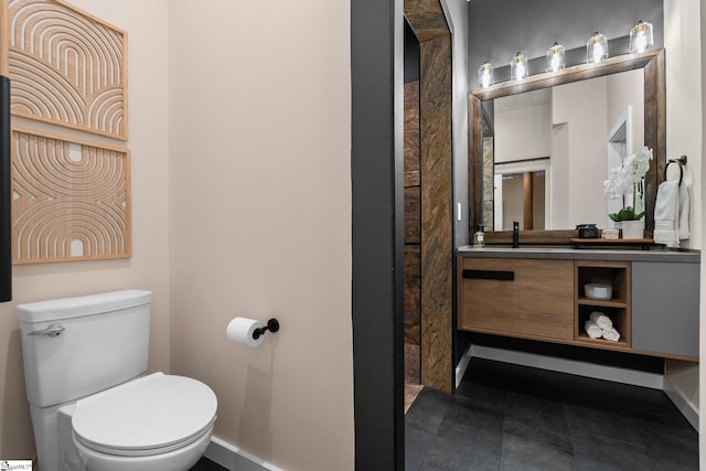 bathroom with baseboards, vanity, and toilet