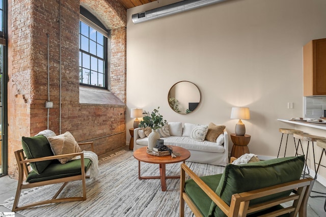 living area with a towering ceiling and brick wall