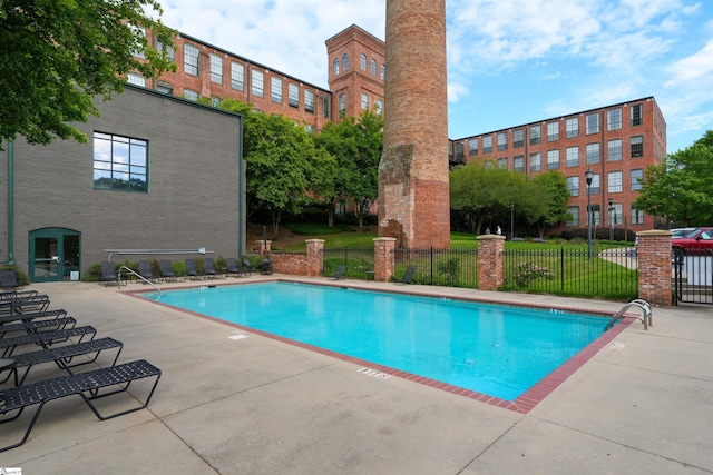 community pool featuring a patio area, fence, and a lawn