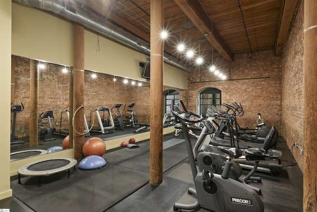 workout area featuring brick wall and a high ceiling