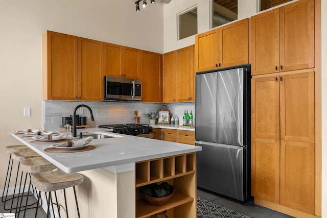 kitchen with decorative backsplash, a high ceiling, stainless steel appliances, light countertops, and a sink