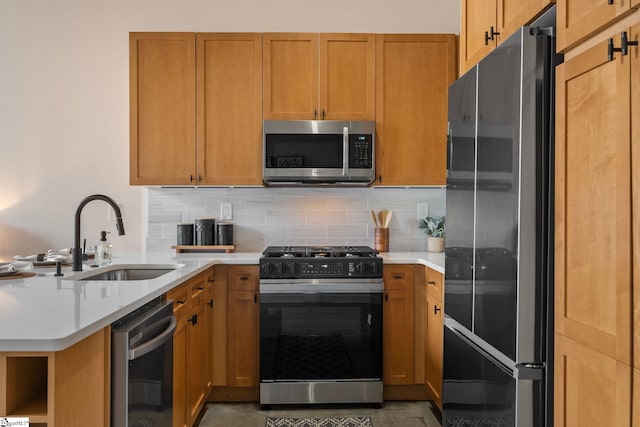 kitchen featuring stainless steel appliances, a peninsula, a sink, light countertops, and backsplash