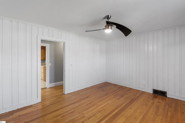 spare room with light wood-style floors, visible vents, and a ceiling fan