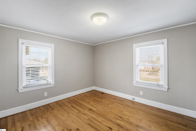 empty room with baseboards, ornamental molding, and wood finished floors