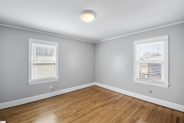 spare room with ornamental molding, a wealth of natural light, and baseboards