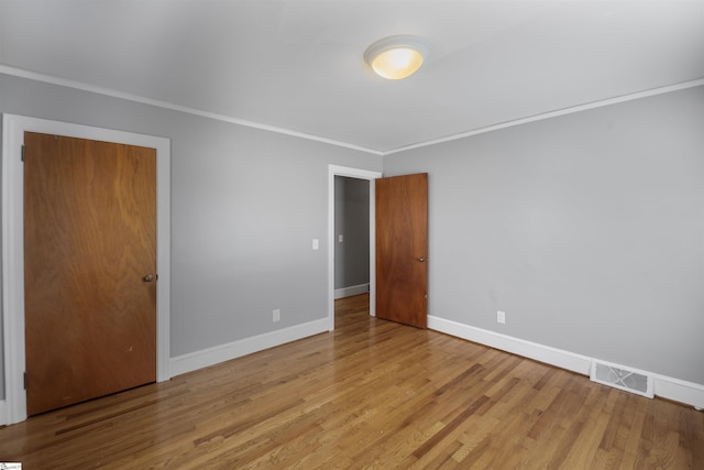 interior space with ornamental molding, light wood-type flooring, visible vents, and baseboards