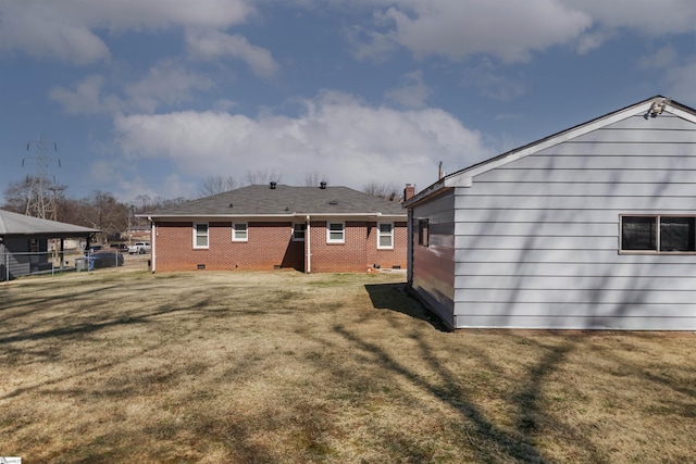 rear view of property featuring crawl space, brick siding, and a yard