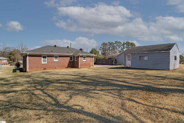 rear view of house with crawl space, brick siding, a lawn, and fence