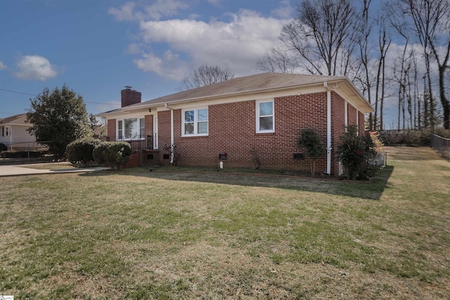 ranch-style house with brick siding, a chimney, and a front yard