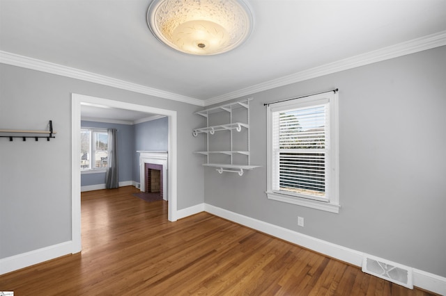 unfurnished dining area featuring visible vents, a fireplace, baseboards, and wood finished floors