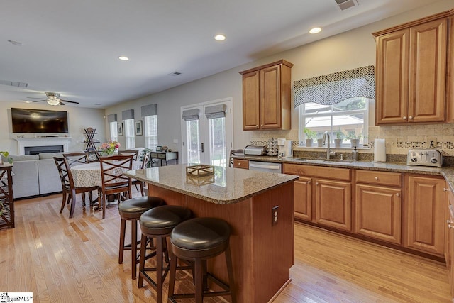 kitchen featuring visible vents, a kitchen island, light wood-style floors, a kitchen bar, and a sink