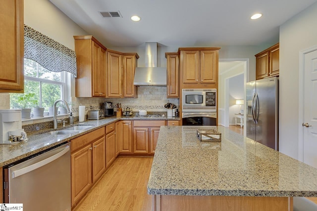 kitchen with a center island, visible vents, backsplash, appliances with stainless steel finishes, and wall chimney range hood