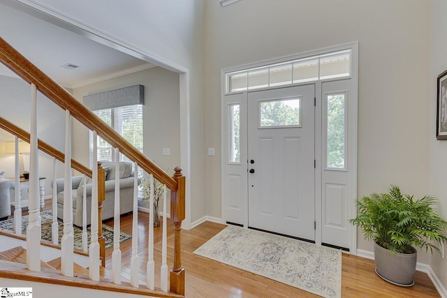 entrance foyer featuring visible vents, baseboards, stairway, wood finished floors, and crown molding