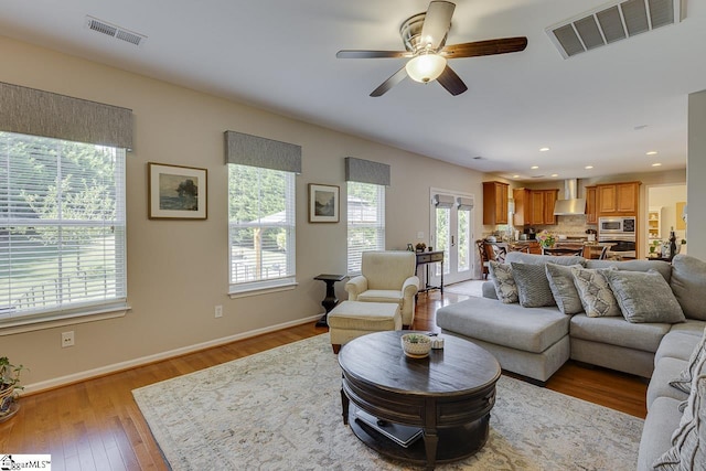 living area with light wood-style flooring, recessed lighting, visible vents, and baseboards