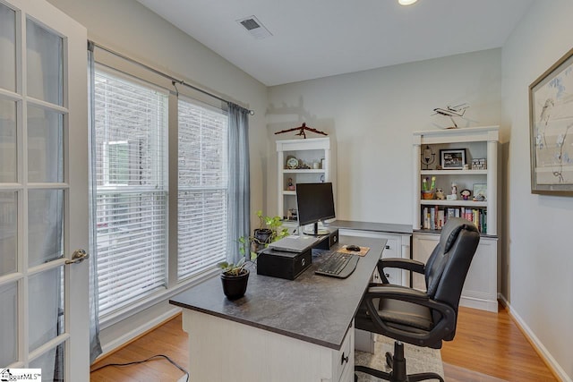 office with light wood-type flooring, baseboards, and visible vents