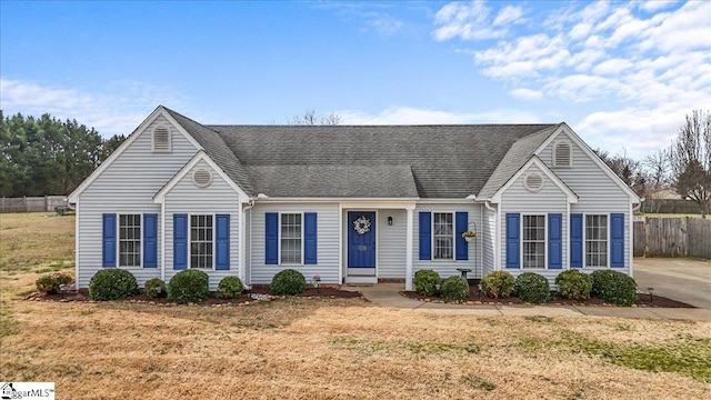 view of front of home featuring fence, a front lawn, and roof with shingles