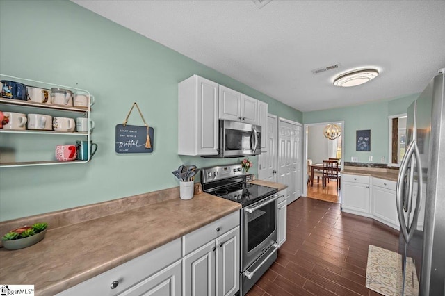 kitchen with appliances with stainless steel finishes, visible vents, dark wood finished floors, and white cabinetry